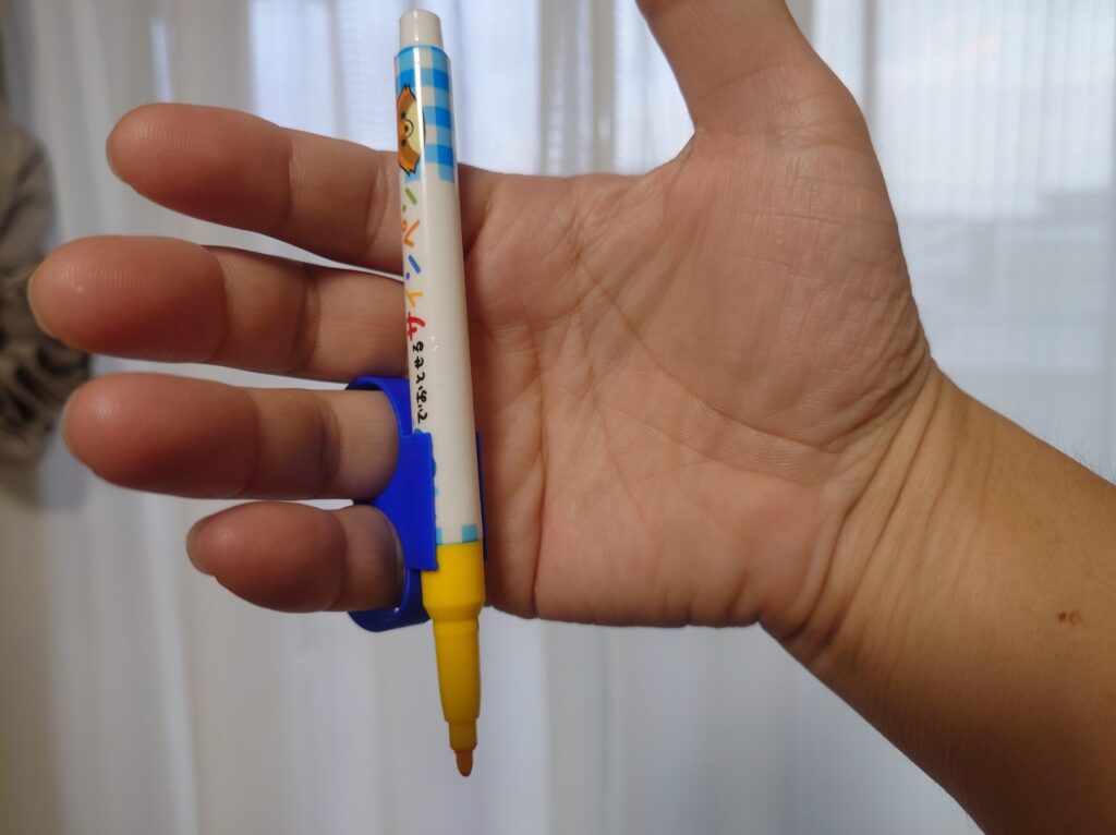 青いホルダーを薬指と小指に通して、サインペンを持っている手の写真