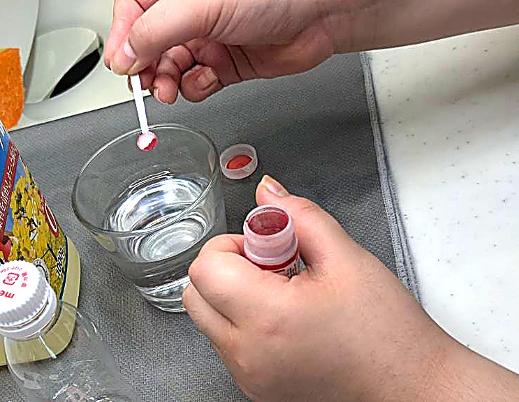 グラスの水に食用色素を落としているところの写真