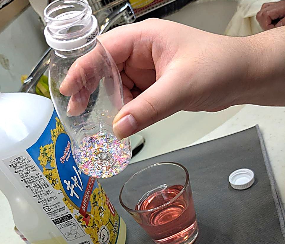 ペットボトルにキラキラした飾りを注ぎ入れているところの写真