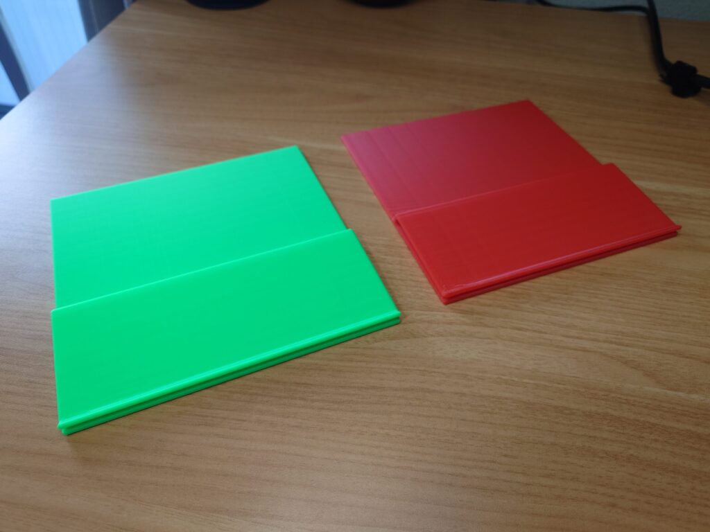 机の上に、緑の旗と赤の旗を1つずつ並べて斜めから撮った写真。下側に挟み込み用の折り返しが付いている