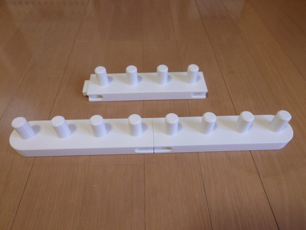 手前で2つの部品をつないで8本のペグが並んだ状態と、奥に未接続の部品が1つ置かれた写真。